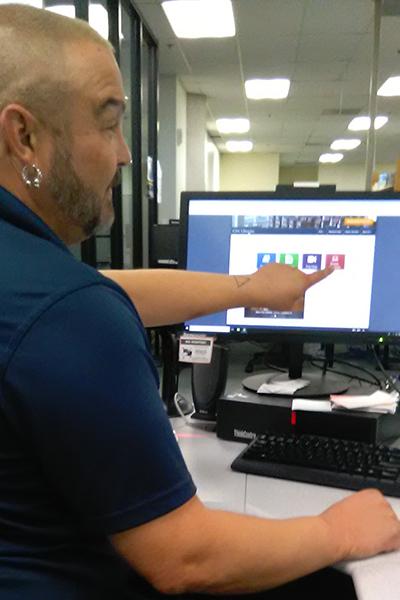 A photo of a CSN librarian pointing at their monitor displaying the CSN Libraries website